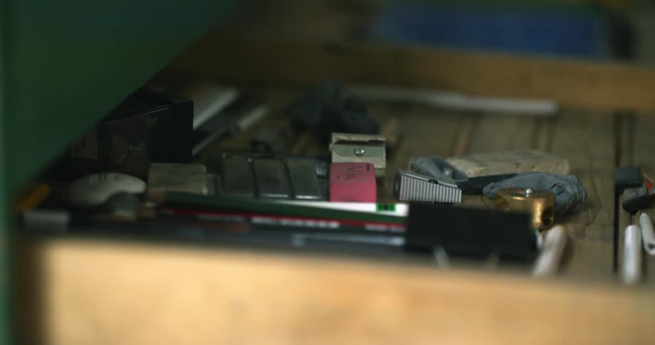 A person opening a drawer and picking up a pink eraser