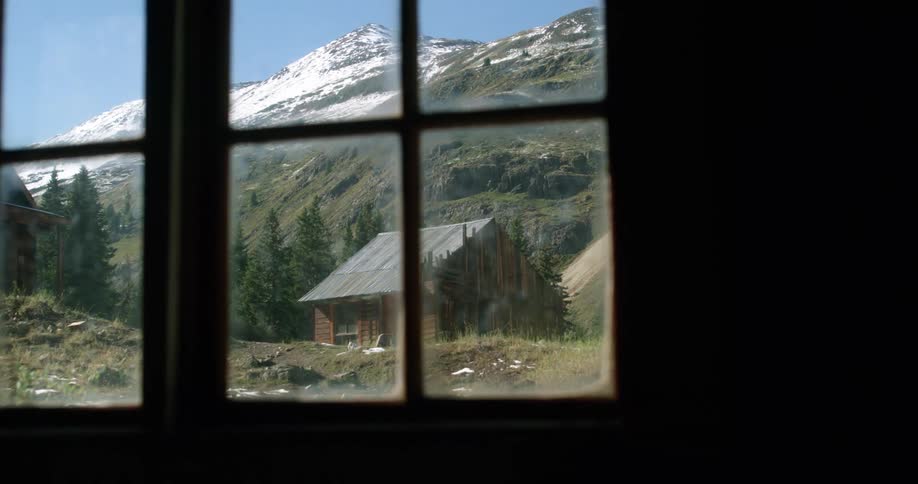 Intermittent snow falls over cabins near snow covered mountains