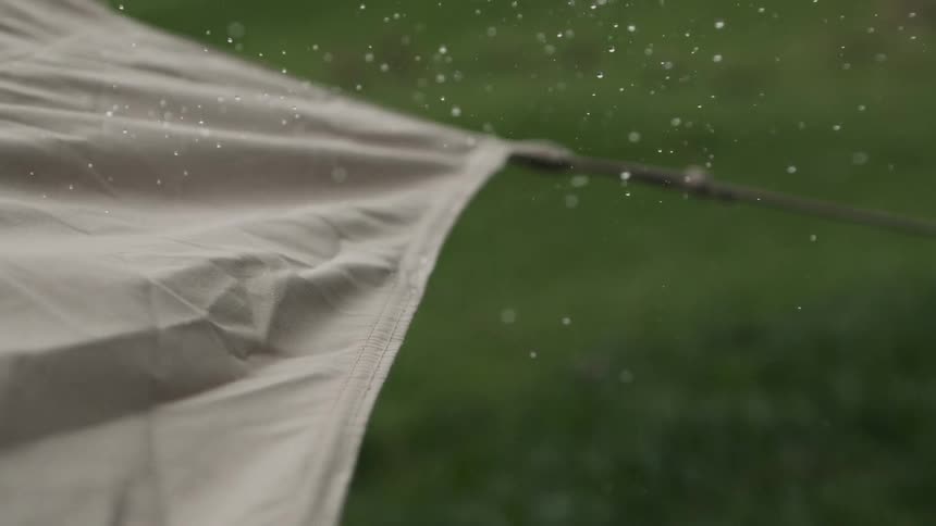 A wet tarp lifts and shakes off drops of water