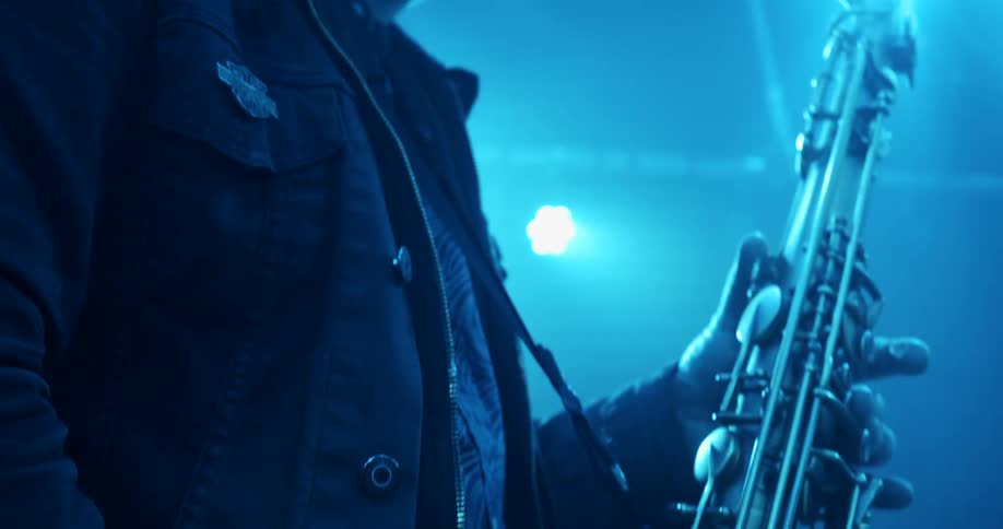 A man plays the saxophone on stage with lights glowing and shining