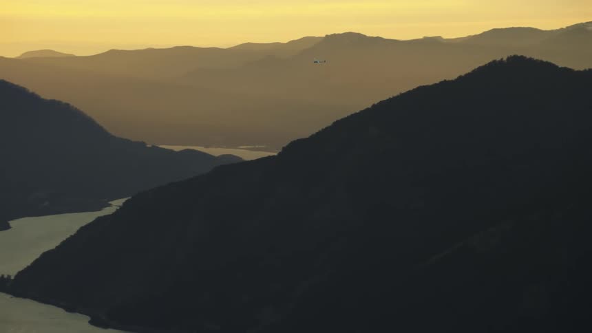 A small glider airplane soars with no engine high above the Columbia River gorge under spectacular sunset light in this air to air aerial shot
