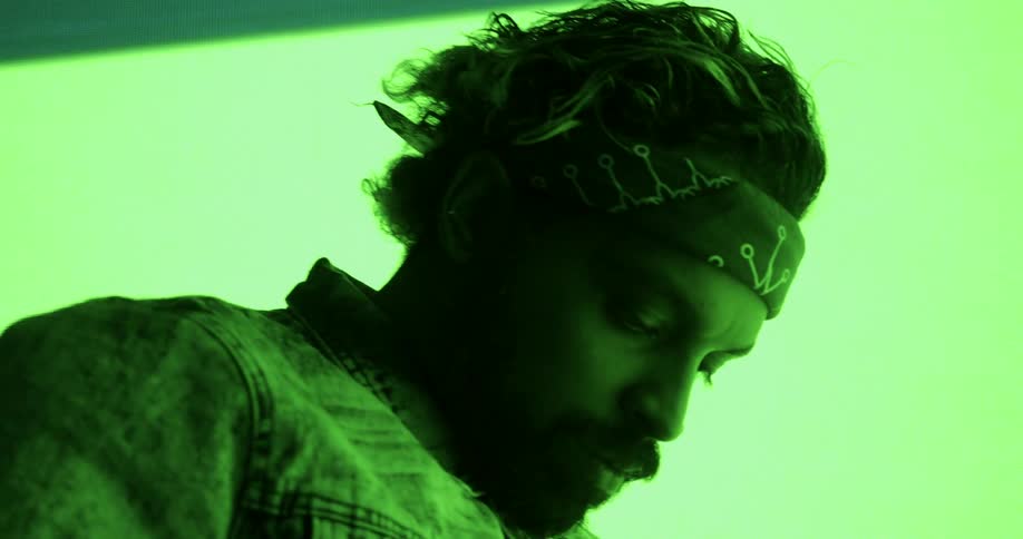 Bright lights flashing behind a man as he puts his head down in thought