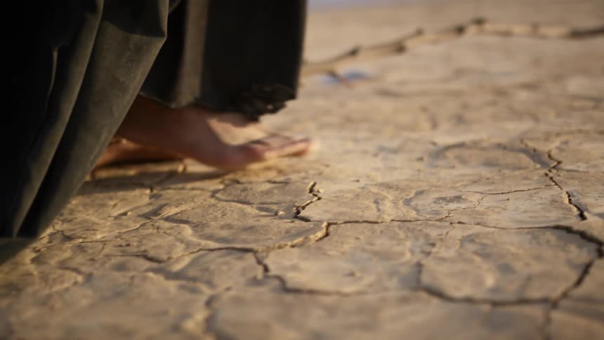 Close up of a mans feet as he walks across a desert