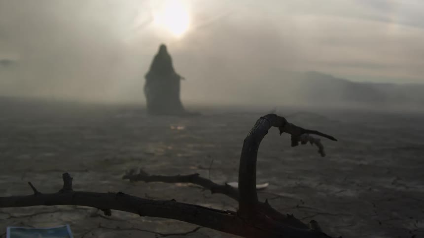 A silhouette of a woman walking across a foggy desert in a long dress