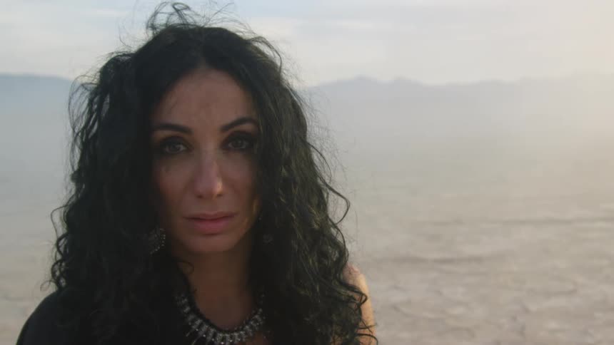 A woman stands frazzled in the desert as dust and fog surround her