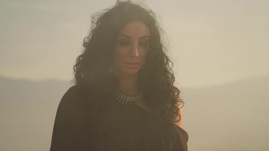 A woman is standing outdoors at dusk