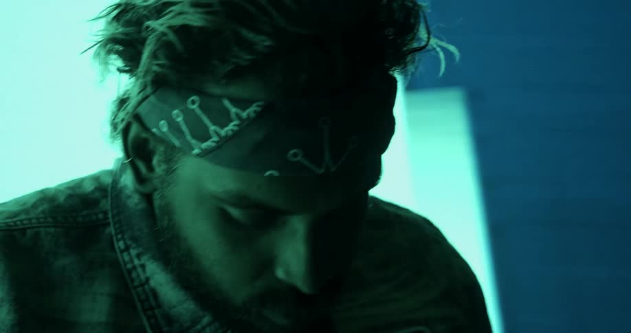 A man with a name tag and bandana on his forehead in front of abstract lights
