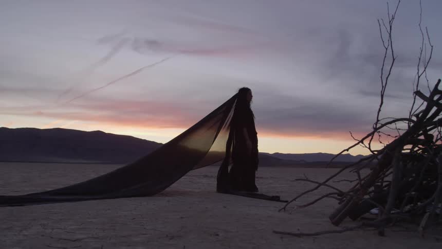 A woman in a dress and veil walking on a dry lake bed