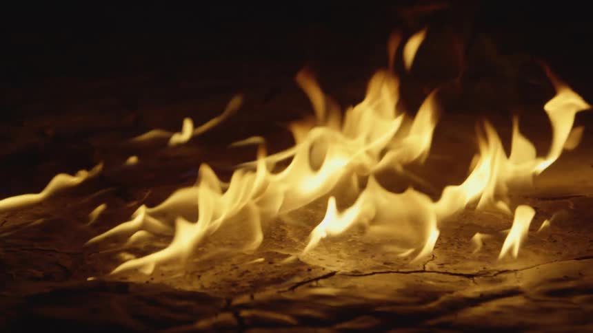 Flames covering the ground are burning in the darkness