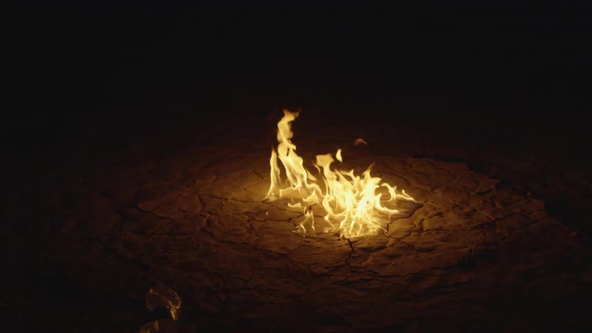 A fire burns from the ground in the desert