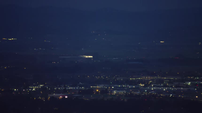A private jet prepares for landing in this blue hour night aerial shot where the runway becomes visible at the end of the shot