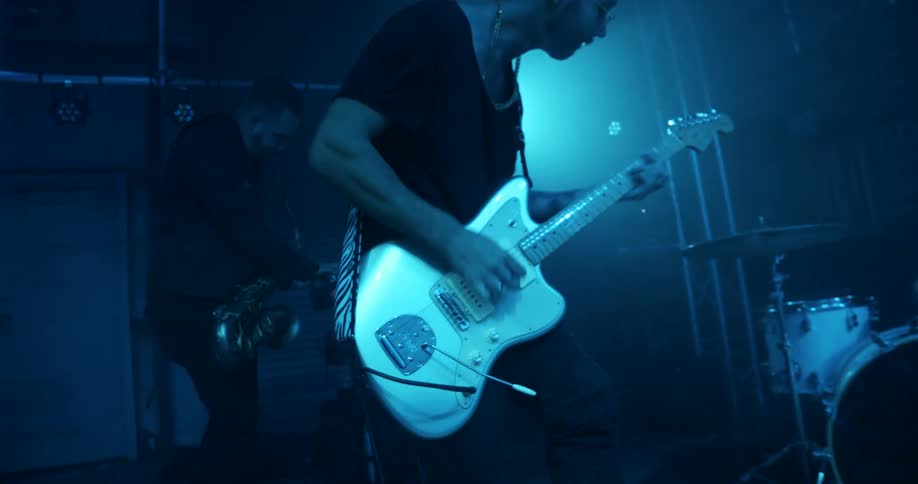 Men on a stage playing instruments with lights flashing in the background