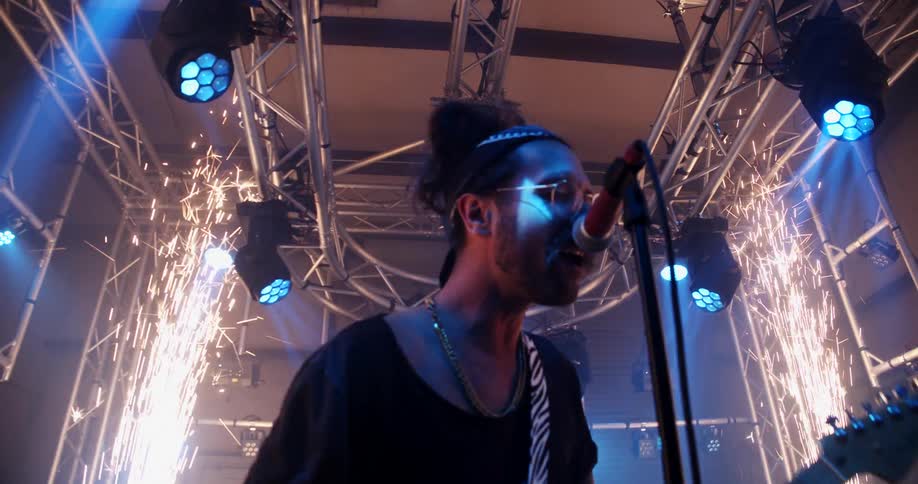 A man singing while playing guitar on a stage