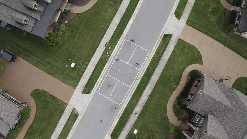 Aerial view of a group of people playing badminton on an improvised court on the street of a neighborhood