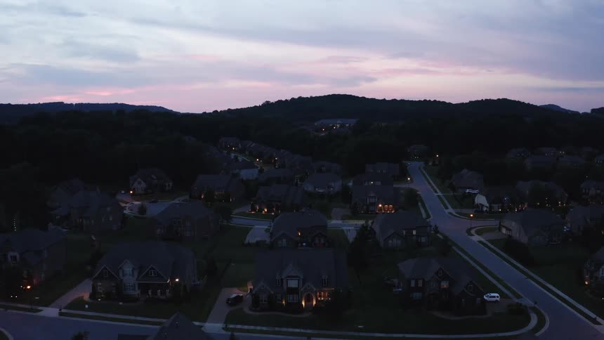 A neighborhood with houses trees and roads with the sky and clouds in the background