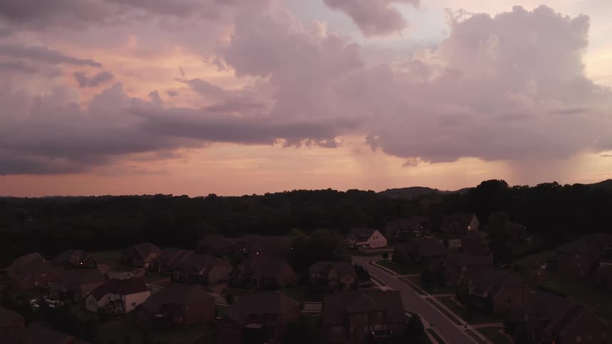 A neighborhood with houses trees and roads with the sky and clouds in the background