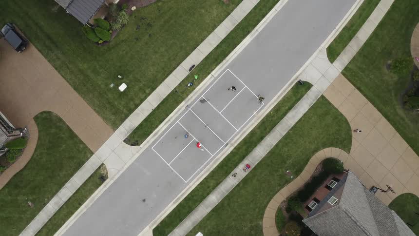 Children playing on a tennis court on a neighborhood street