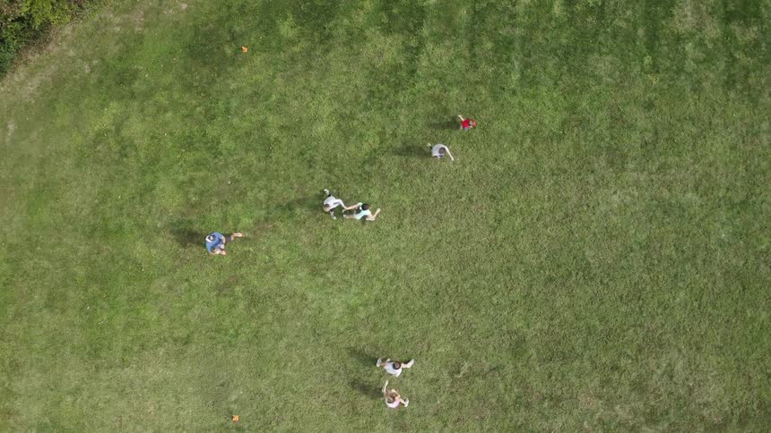 People running on a grassy field playing rugby with a ball