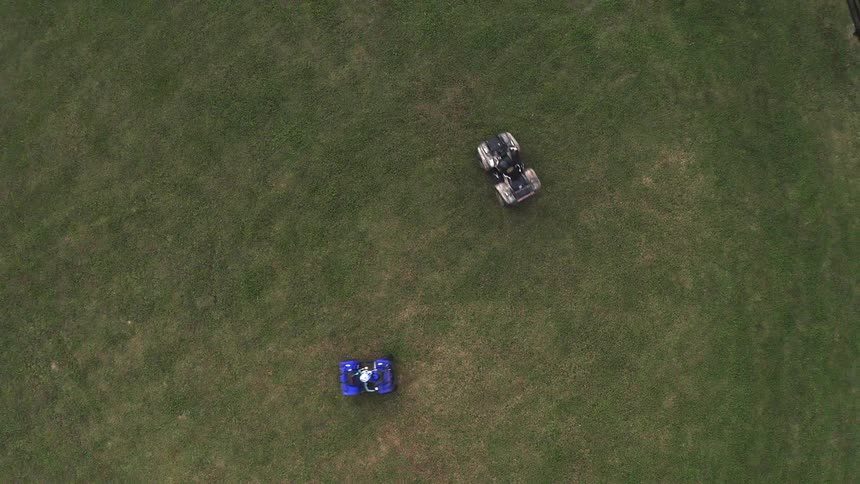 An aerial view of people driving cars in a circle on grass