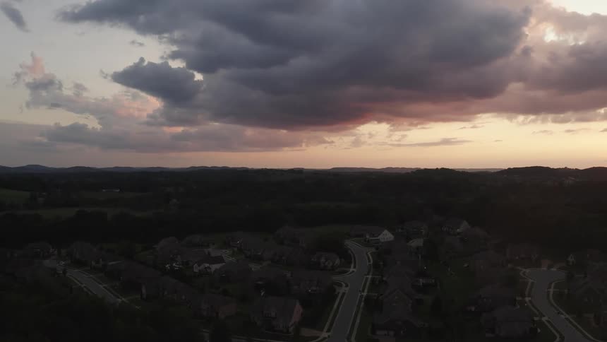 Neighborhood village with the sun on the horizon under a cloudy sky