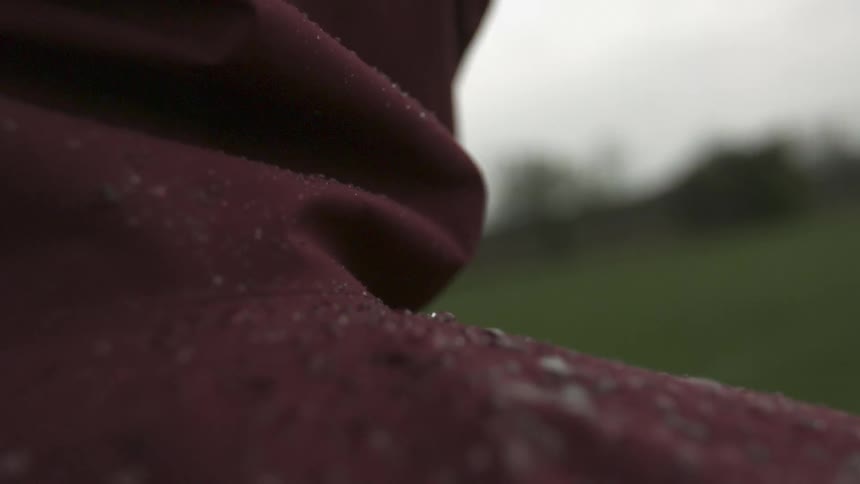 Close up of a jacket on a person covered with rain drops
