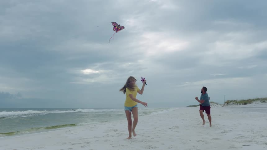 A man and woman playing with a kite on a beach