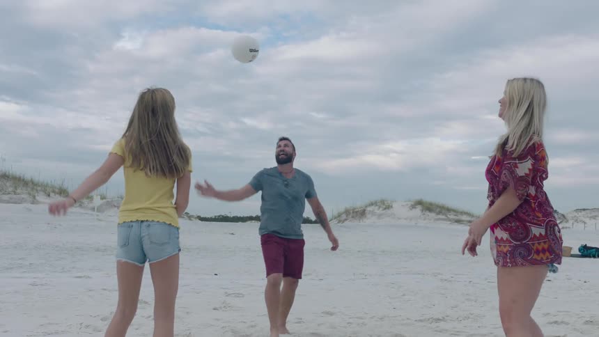 Family playing with a volleyball over the sand of a beach