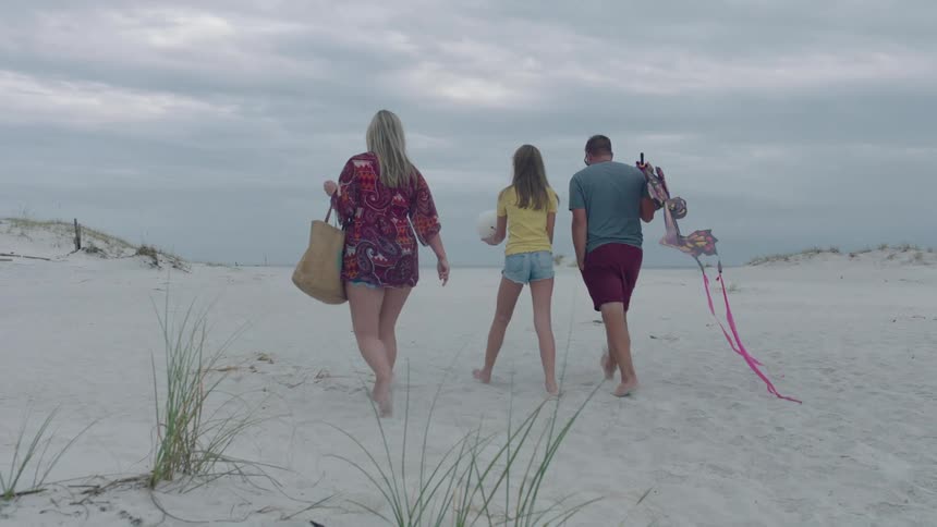 A group of three people walking down the beach