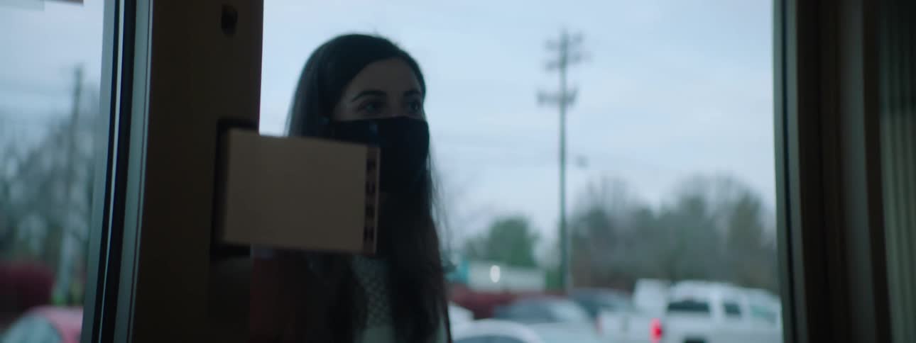 Woman wearing a black face mask knocks on the glass door of a store