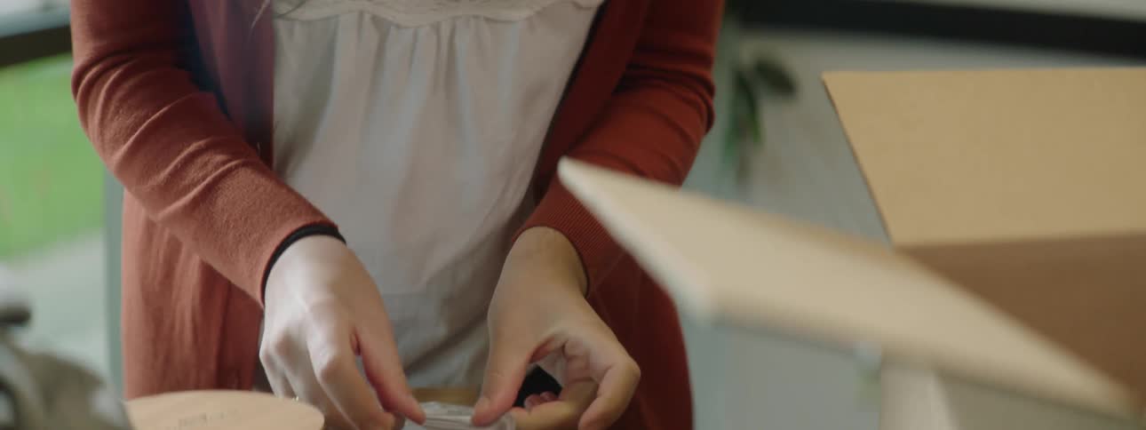 Woman working on a store puts a round sticker on a brown paper bag