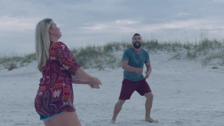 Family playing volley ball on the sand at the beach on a cloudy day