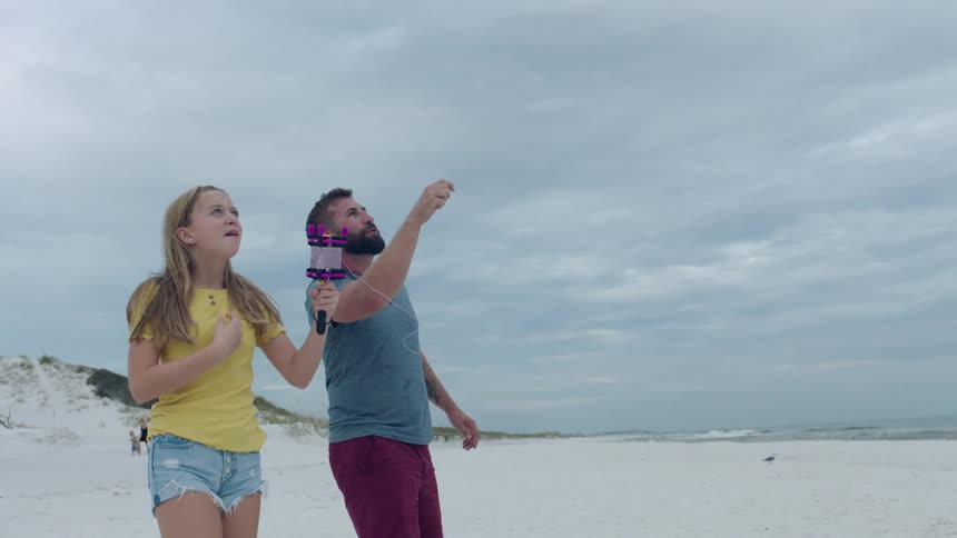 A father and daughter playing with a kite at the beach