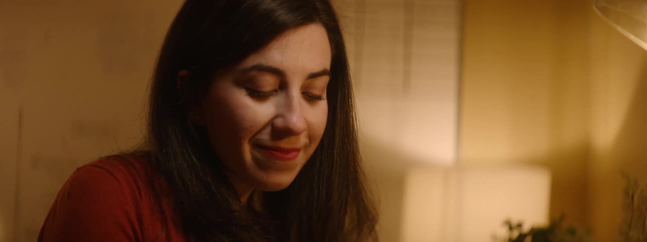 A woman sits at her desk while writing before looking up and smiling
