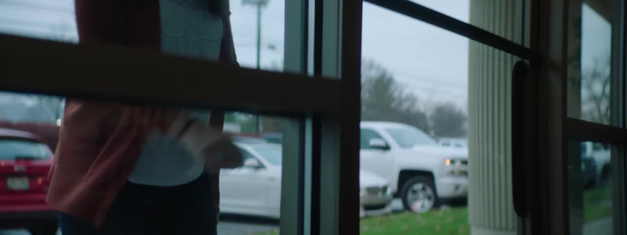 A woman with a mask placing a box in front of a building and knocking on the door