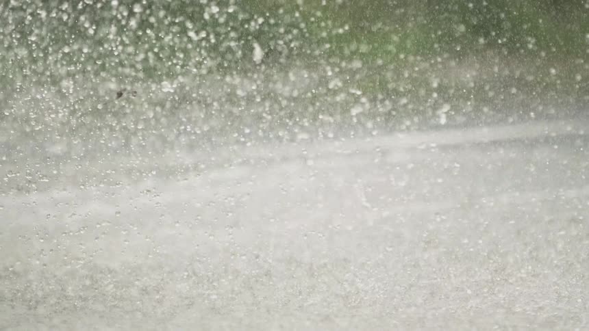 Water is splashed up from the road by a passing car