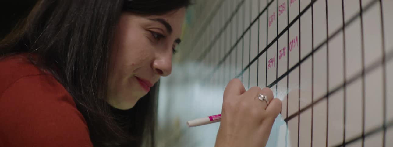 Woman writing on a whiteboard with a pink pen in the office
