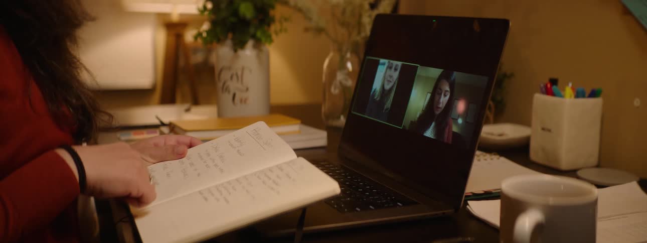 A woman nods talks and laughs as she participates in a meeting on her laptop
