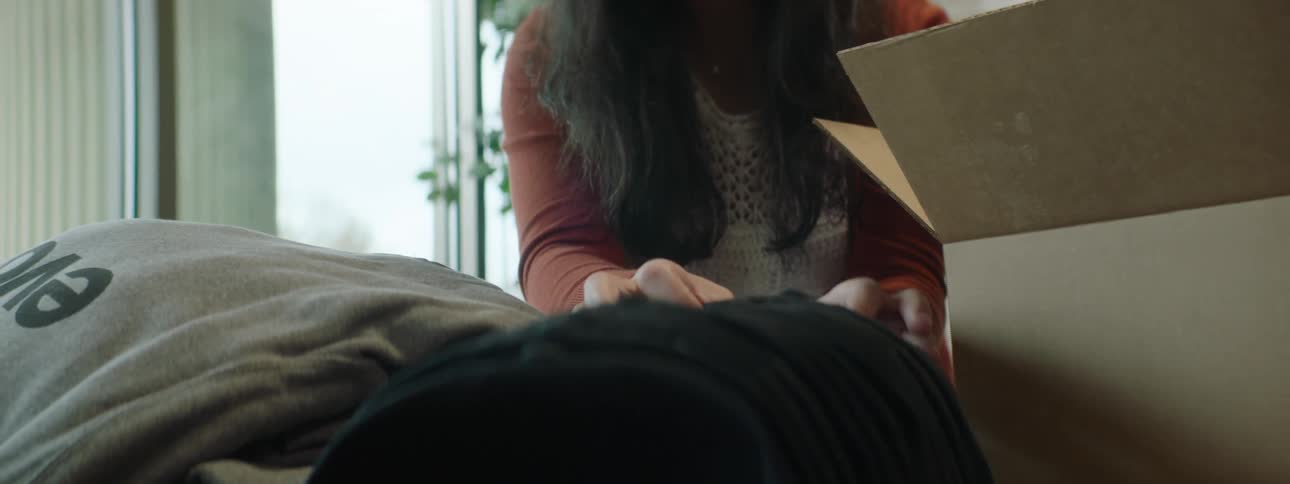 Woman unpacking baseball caps from cardboard boxes
