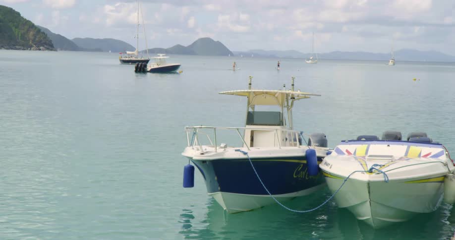Boats floating near a pier in the calm ocean waters close to the mountains