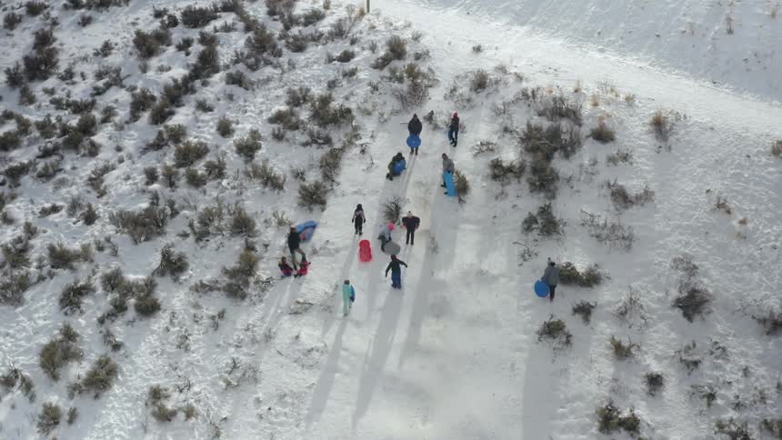 A group of people carry and ready small sleds in a snowy field