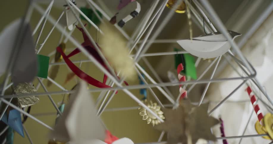 A baby mobile hangs from the ceiling of a room in a house during the day