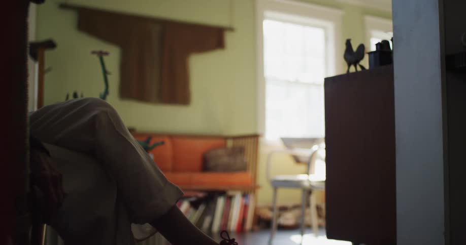 A person sitting on a chair in a room with a wall and windows in the background