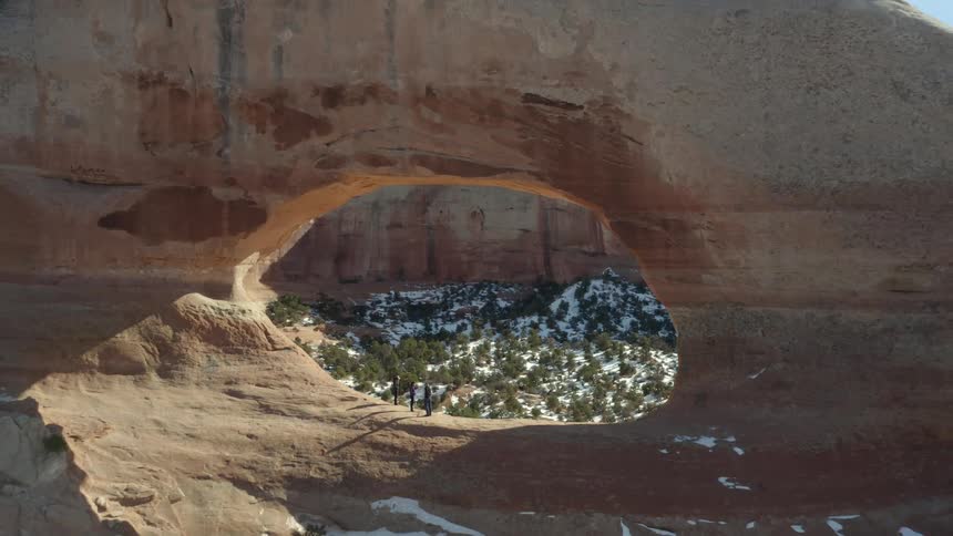 People standing on a cliff with trees and snow with the sky and clouds in the background