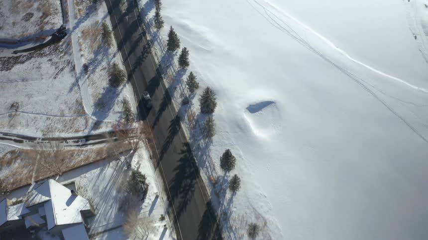 An aerial view of cars traveling on a neighborhood road on a cold winter day