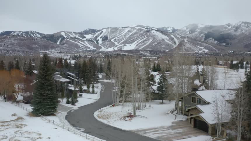A snow covered gated community at the base of mountains with ski trails