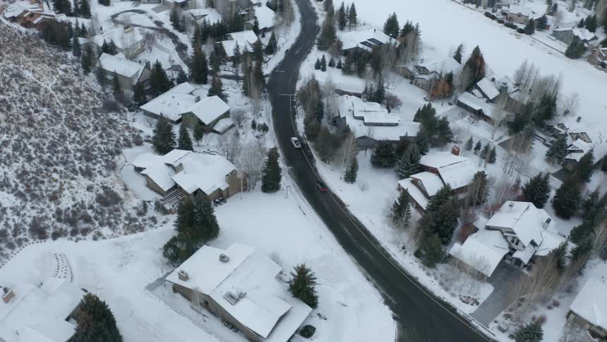 A town with houses a road with vehicles and trees covered in snow
