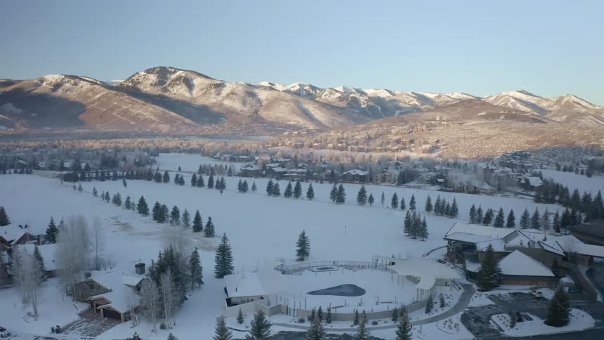 Aerial view of a snow covered town in the plains near a mountain range in the morning