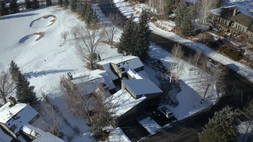 A town with snow covered houses and trees with streets with vehicles