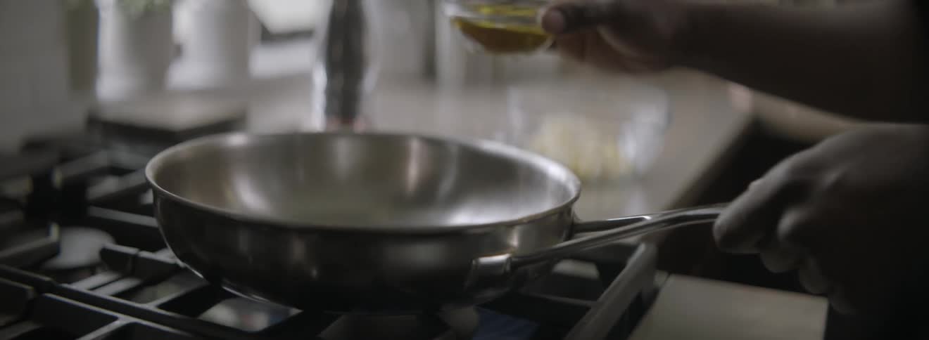 Measured portion of oil is poured into a pan on a stove