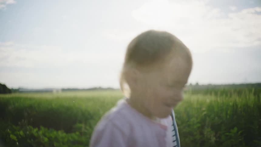 Two children walking on a path holding hands with a grassy field the sky and clouds in the background